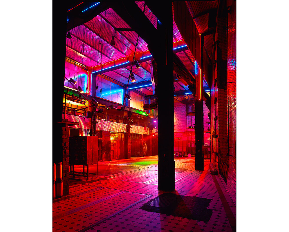 Interior view of E-Werk with colored light installations across the tiled hall.